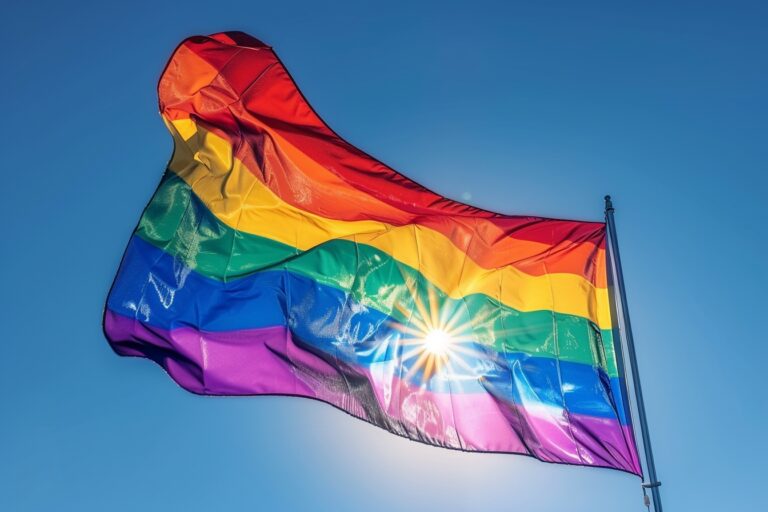 Groupe diversifié tenant un énorme drapeau arc-en-ciel lors de la Journée mondiale contre l'homophobie
